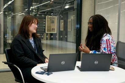 student intern sitting at desk with manager and two open laptops