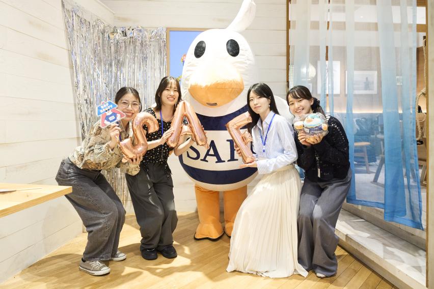 4 students pose next to SAFFY mascot, all holding SAF merch.