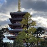 The Sensoji tower with trees and clouds framing it. The tower has a large golden spire at the top.