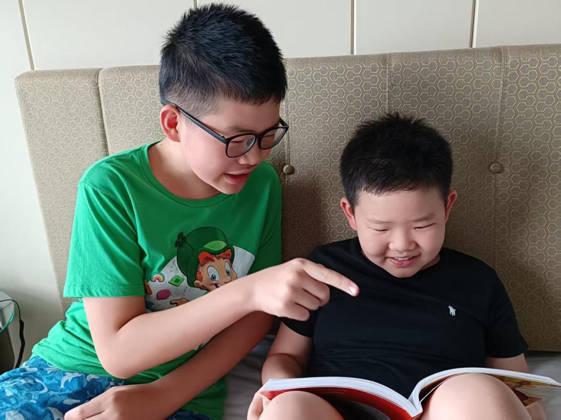 직원 Gorden Xie의 큰아들이 동생이 책 읽는 것을 도와주고 있는 모습.