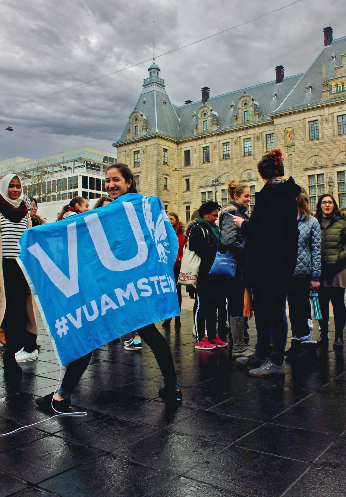 a student walking with a VU flag on a rainy day