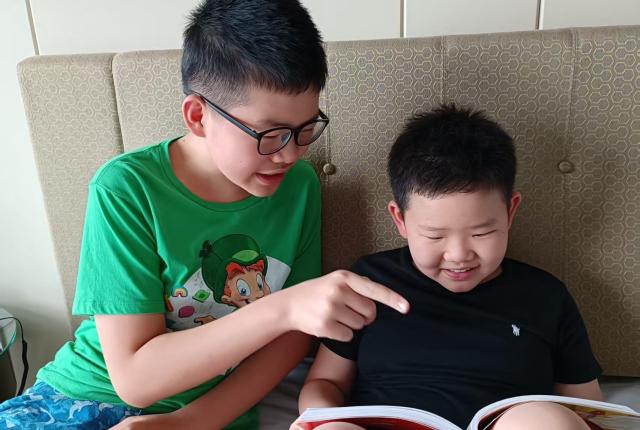 직원 Gorden Xie의 큰아들이 동생이 책 읽는 것을 도와주고 있는 모습.