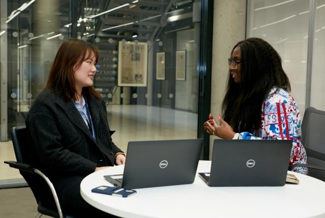 student intern sitting at desk with manager and two open laptops