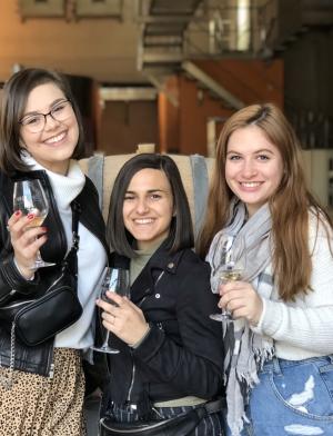 a group of students holding wine glasses and smiling at the camera