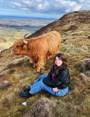 A student poses with a cow in the scottish highlands