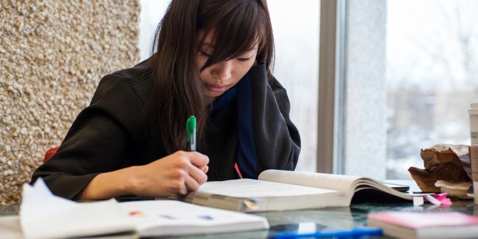 A young Korean woman studies an English language textbook for the TOEFL exam